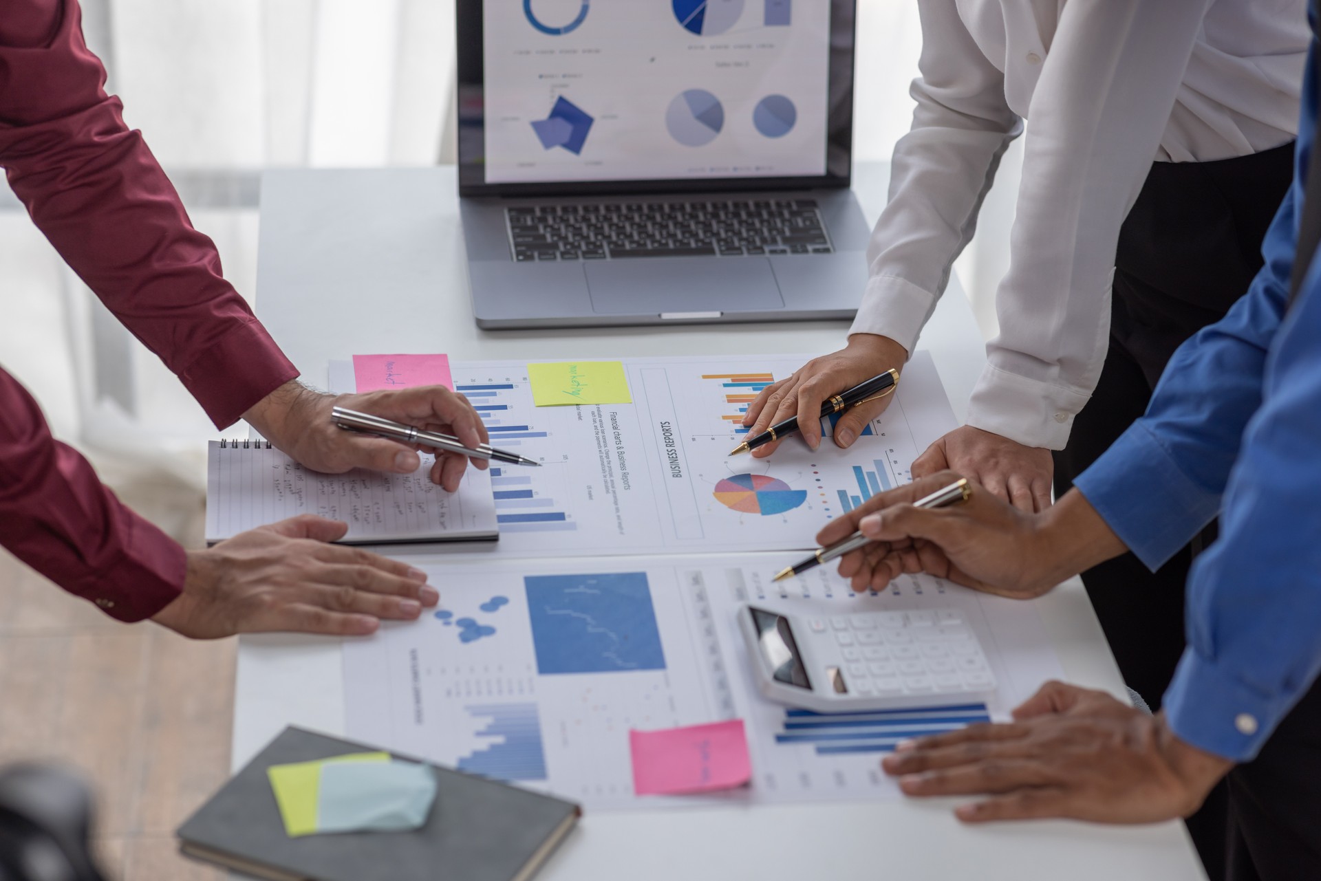 Group of confident business people point to graphs and charts to analyze market data, balance sheet, account, net profit to plan new sales strategies to increase production capacity.